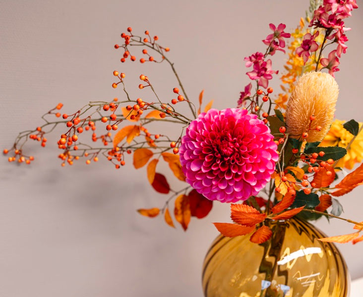 Zijden boeket genaamd Natasja in rijke herfstkleuren zoals roze, geel en oranje, gepresenteerd in een unieke mondgeblazen amberkleurige Fridio vaas (30 x 35 cm) van BloomFever.