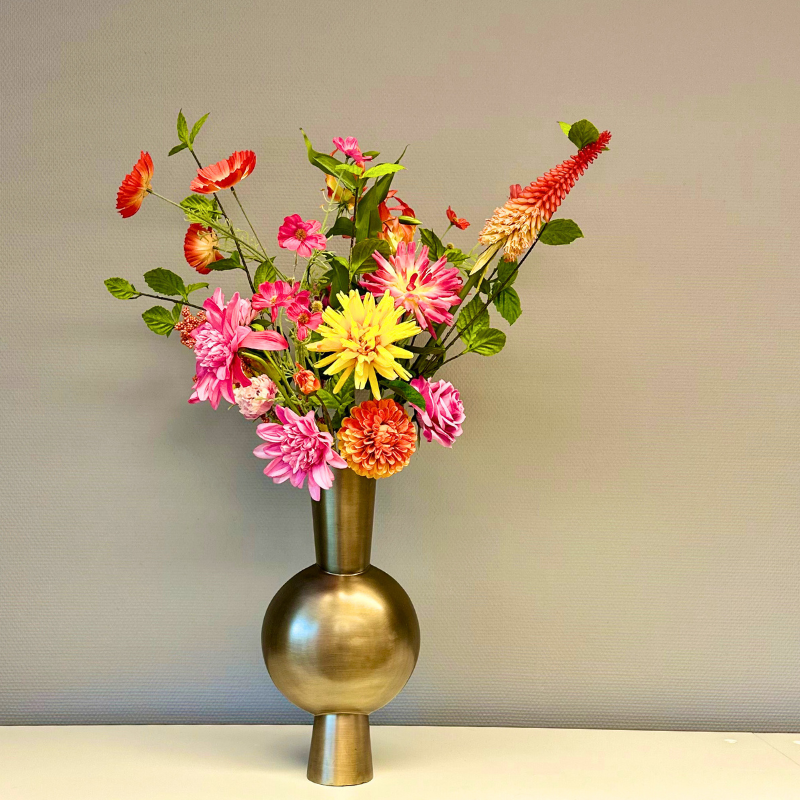 Zijden boeket Paradiso met kleurrijke bloemen zoals dahlias, anjers, zinnia's en een fakkellelie, gepresenteerd in een bronzen Kavandu Medium vaas. Het boeket straalt elegantie en vrolijkheid uit, perfect voor elke interieurstijl.