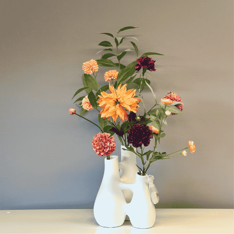 Zijdenbloemen in Connection vaas mat wit. Kunstbloemen zijn Dahlia, sranokel, anjer in trendkleuren herfst