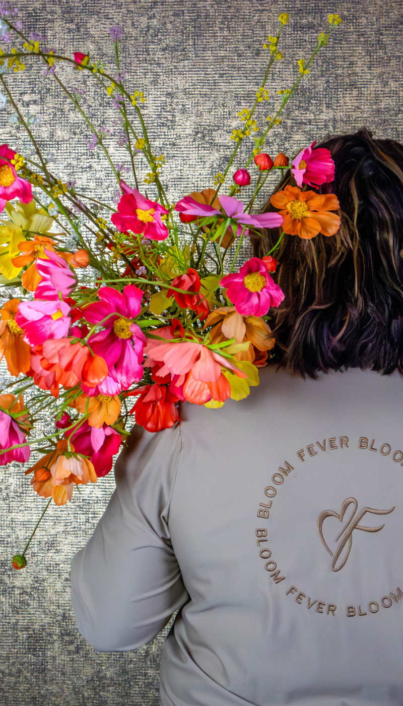 zijden cosmosbloemen in de kleuren geel, oranje, fuchsia en rood. Gepresenteerd als zijden boeket met bedrijfskleding van BloomFever 