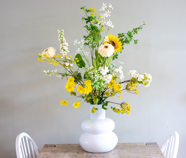 kunstboeket van zijden bloemen in de kleuren geel, wit en groen. Gepresenteerd in witte bubbelvaas uit collectie van BloomFever.