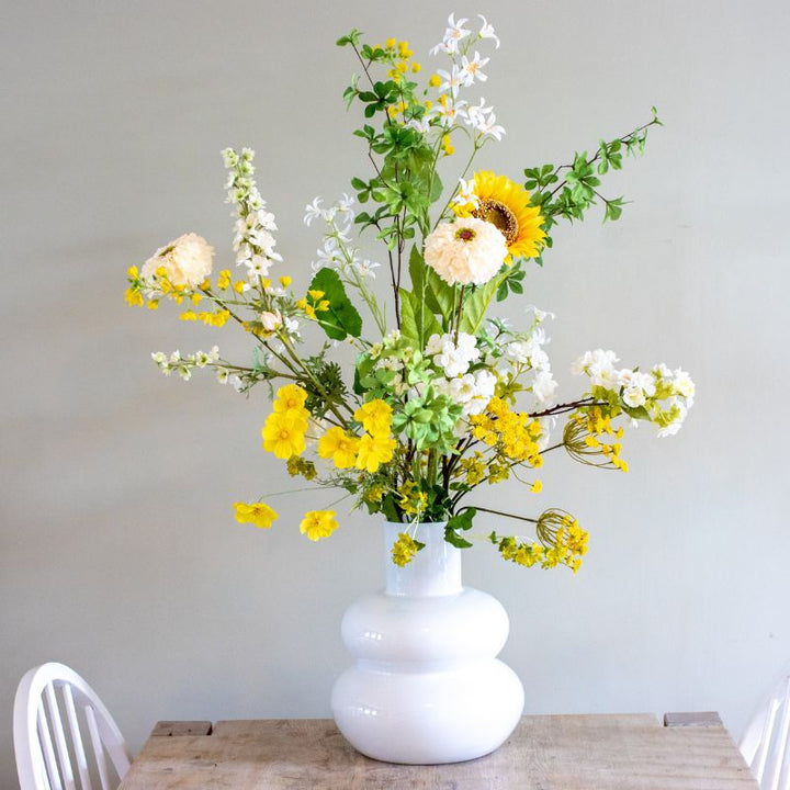 kunstboeket van zijden bloemen in de kleuren geel, wit en groen. Gepresenteerd in witte bubbelvaas uit collectie van BloomFever.