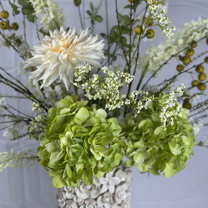 Zijdenbloemenboeket Flore van BloomFever in frisse groene en witte tinten met hortensia's, dahlia's, madeliefjes, Eremus stelen, sneeuwballetjes, groene appeltjes en eucalyptus blad, gestyled in een luxe vaas
